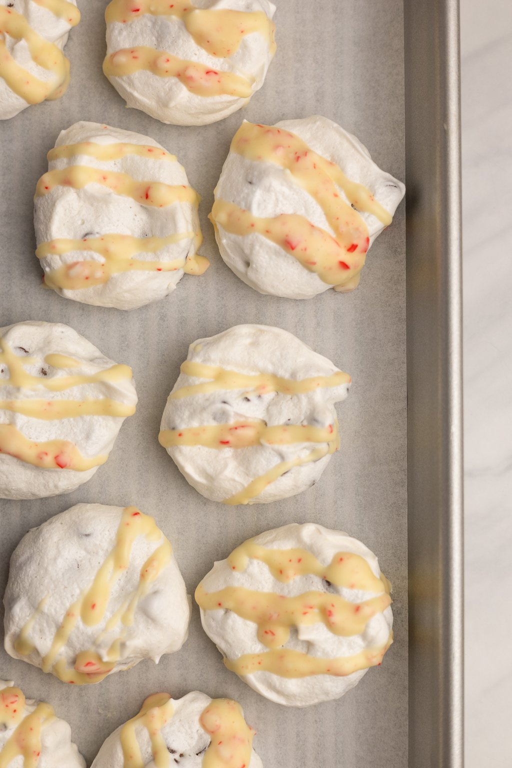 chocolate chip meringues on a sheet pan with icing drizzled